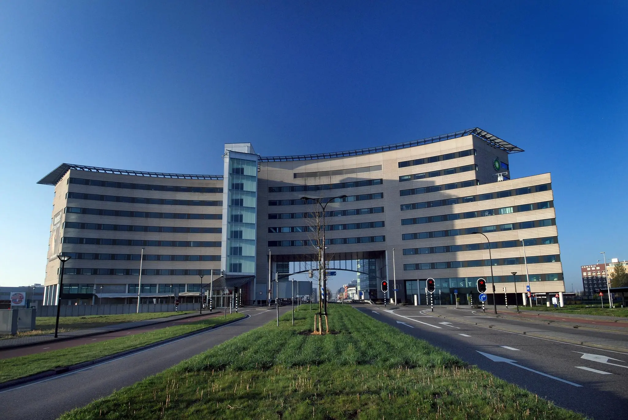 Modern kantoorgebouw aan het Rivium Boulevard met gebogen gevel en centrale doorgang over de weg.
